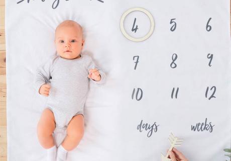 Schöne Foto-Idee: Mit der Meilenstein-Decke halten die Eltern die spannende Entwicklung ihres Babys fest